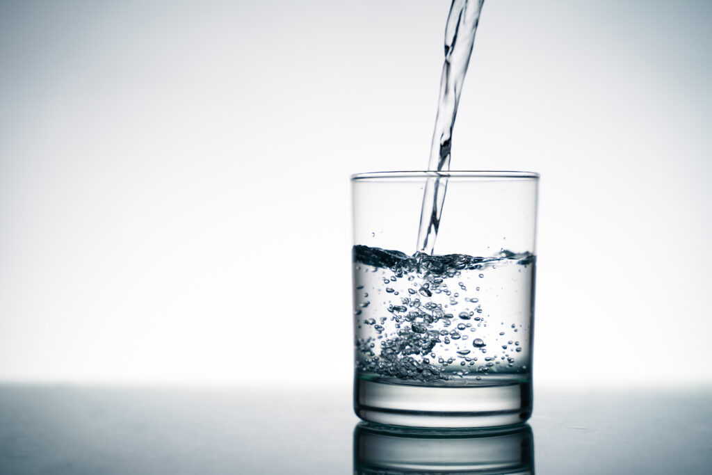 Close up of pouring fresh water into the clear glass