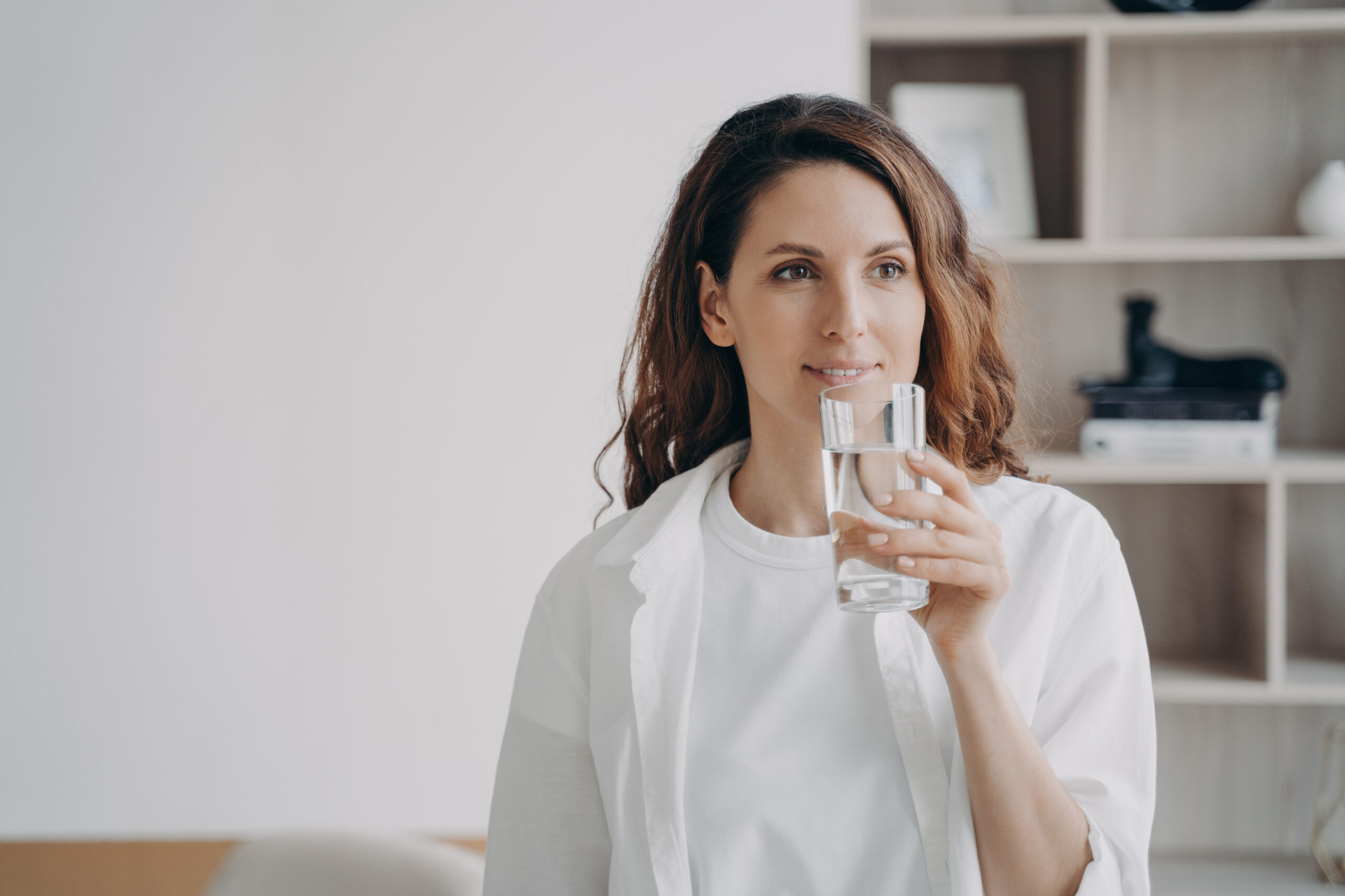 Relaxed european woman is drinking pure water at home